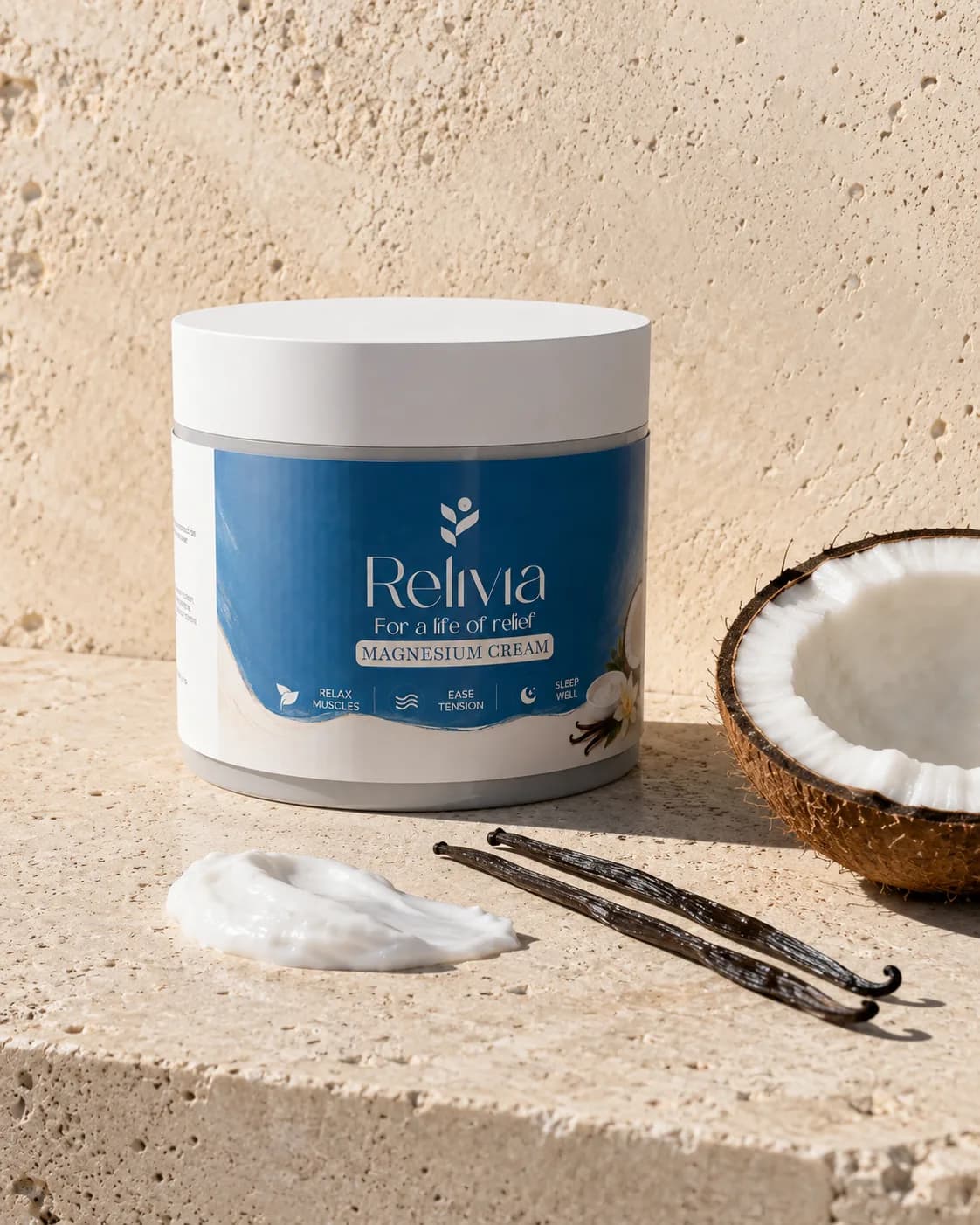 The jar on sunlit stone beside a halved coconut, vanilla pods and a smear of the cream